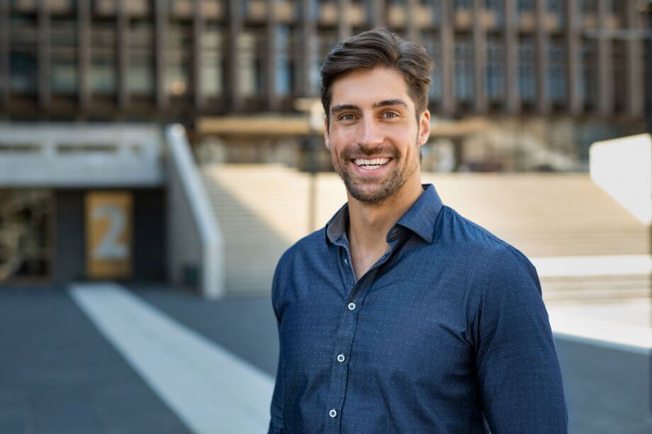 smiling man in blue shirt standing outside office building