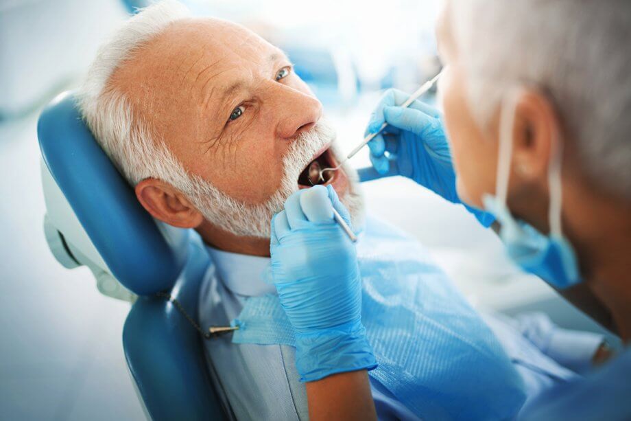 older man getting examined by dentist