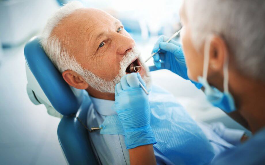 older man getting examined by dentist