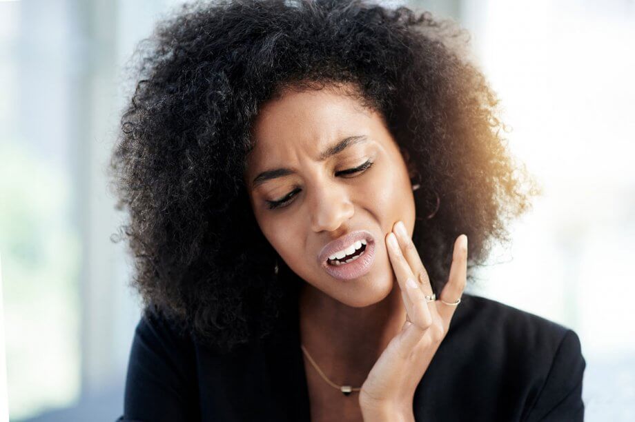 woman holding jaw in pain